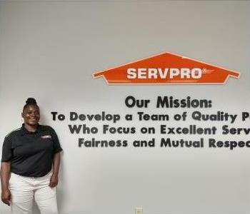 young black woman with black hair in a bun wearing a black SERVPRO polo.