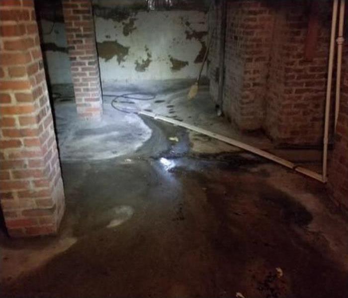 water on floor of basement and two brick columns to the left. 