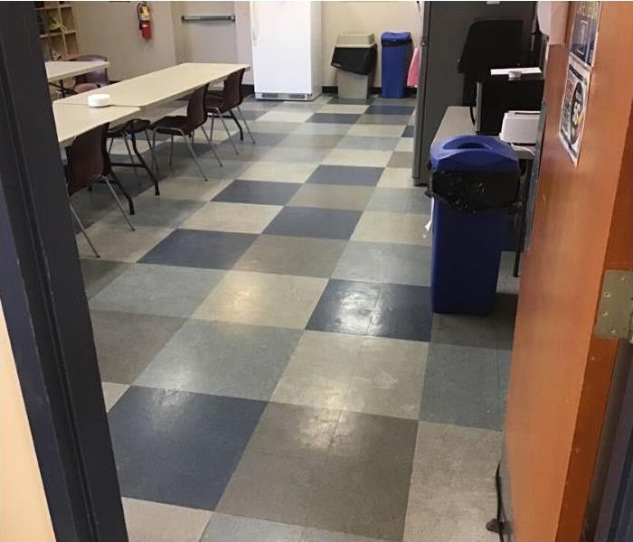 cafeteria room with tiled floors, blue trash can, long tan tables, and burgundy chairs.