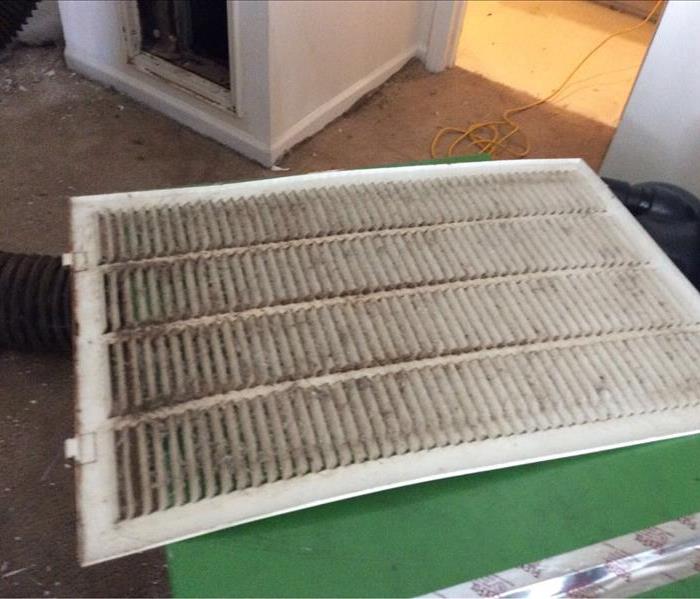 Dirty air filter on top of brown carpet littered with particles. 