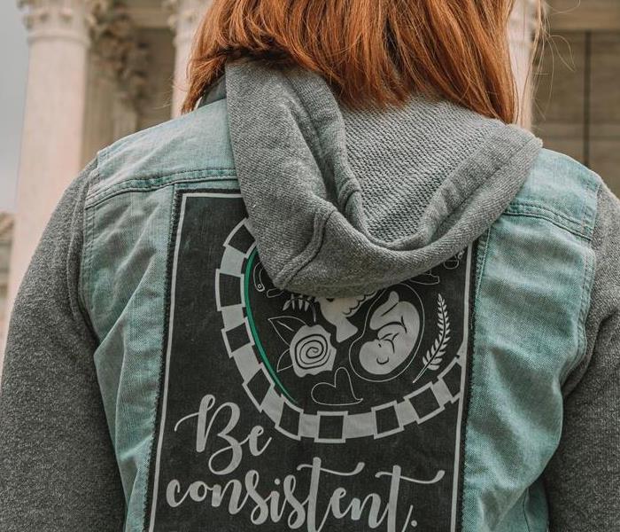 A woman wearing a vest that says "be consistent"