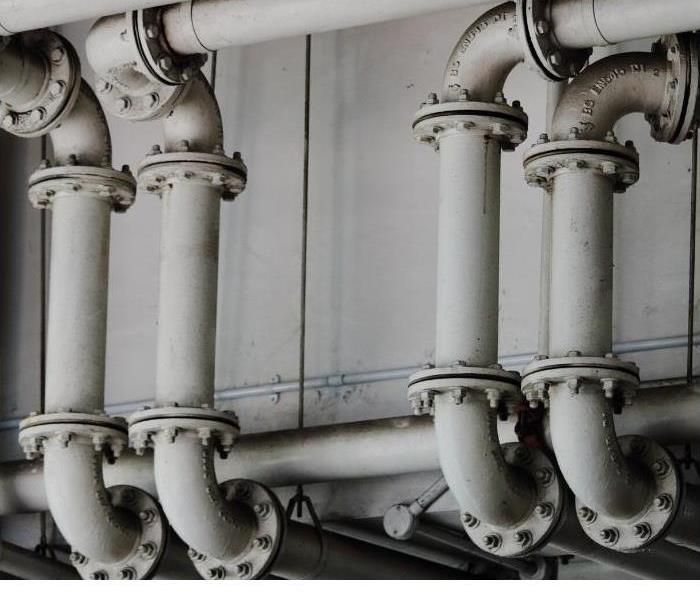 collection of gray pipes screwed together and against a solid wall