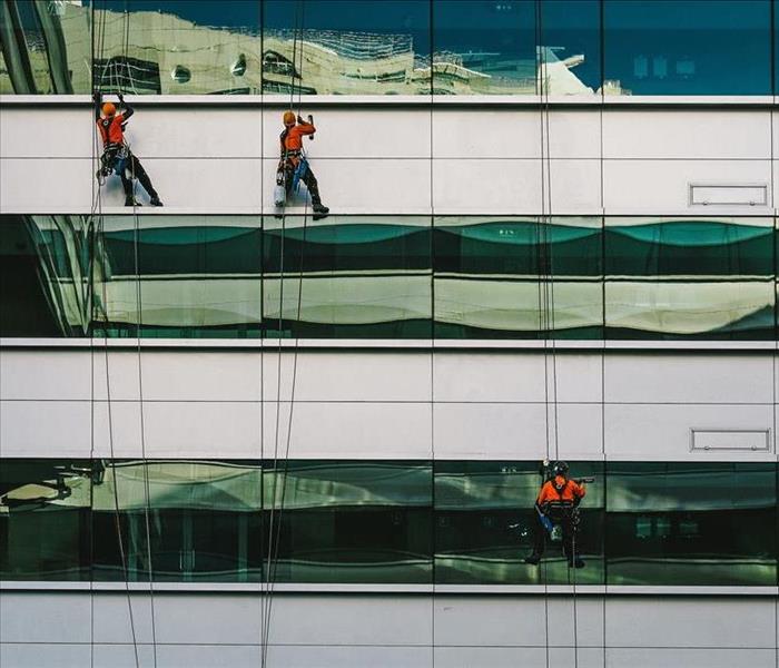 Men clean the outside of a building on scaffolds